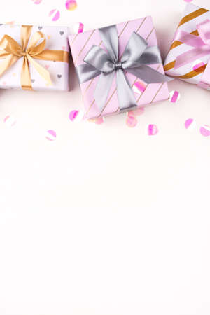 Gift boxes with bows and confetti on a white background. Flat lay composition. Birthday, christmas, wedding or another holiday concept.の写真素材