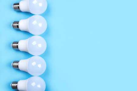 Several LED bulb on blue background. Saving energy concept. Ftat lay, top view, copy space.