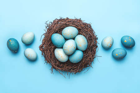 Easter eggs in nest on blue background. Flat lay, top view.の写真素材
