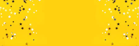 Golden and silver stars on yellow background. Flat lay, top view.の写真素材