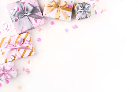 Several gift boxes with bows and confetti on a white background. Flat lay composition. Birthday, christmas, wedding or another holiday concept.の写真素材