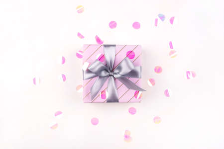 One gift boxe with bow and confetti on a white background. Flat lay composition. Birthday, christmas, wedding or another holiday concept.の写真素材