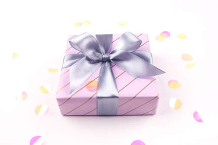 One gift boxe with bow and confetti on a white background. Flat lay composition. Birthday, christmas, wedding or another holiday concept.の写真素材