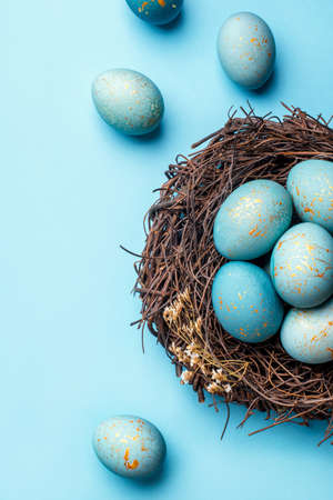 Easter eggs in nest on blue background. Flat lay, top view.の写真素材