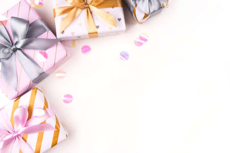 Several gift boxes with bows and confetti on a white background. Flat lay composition. Birthday, christmas, wedding or another holiday concept.の写真素材