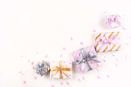 Several gift boxes with bows and confetti on a white background. Flat lay composition. Birthday, christmas, wedding or another holiday concept.の写真素材
