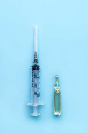 Medical ampoule with the drug and a disposable syringe on a blue background. Medicine infectious concept.の写真素材