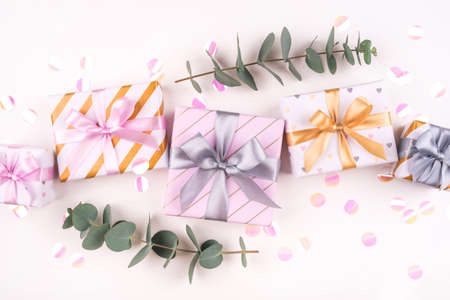Set of gift boxes with bows, eucalyptus branches and confetti on a white background. Flat lay composition. Birthday, christmas, wedding or another holiday concept.の写真素材