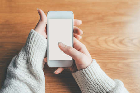 Womans hands holding phone with white screen. Copy space for your text message.の写真素材