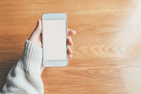Womans hand holding phone with white screen. Copy space for your text message.の写真素材