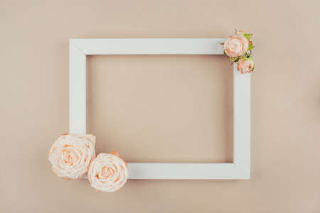 Spring background. Rose flowers and white frame on a beige background. Flat lay. Copy space for your text.の写真素材