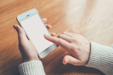 Womans hands holding phone with white screen. Copy space for your text message.の写真素材