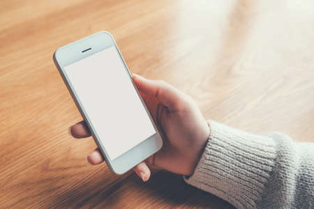 Womans hands holding phone with white screen. Copy space for your text message.の写真素材