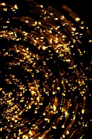 Gold confetti on black background. Flat lay, top view. Long exposure.の写真素材