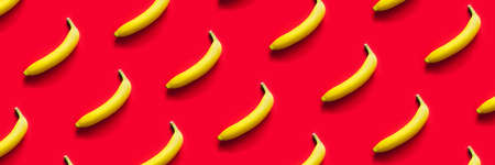 Pattern of yellow bananas on a red background. Flat lay.の写真素材