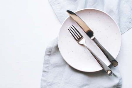 An empty plate and Cutlery on a white table. Top view.の写真素材