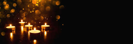 Several burning candles with festive bokeh on a black background. Banner with copy space.の写真素材