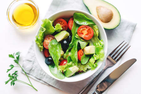 Fresh salad of avocado, cherry, arugula and olives made at home. Vegan food. The concept of healthy eating. Top view.の写真素材