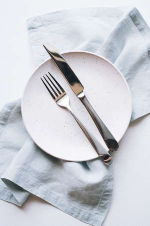 An empty plate and Cutlery on a white table. Top view.の写真素材