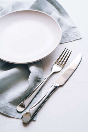 An empty plate and Cutlery on a white table. Top view.の写真素材