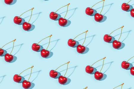 Bright pattern of ripe cherries on a blue background. Flat lay, top view.の写真素材