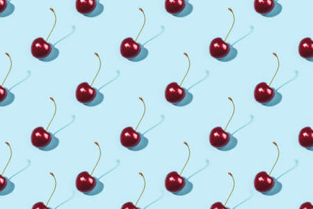 Bright pattern of ripe cherries on a blue background. Flat lay, top view.の写真素材