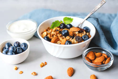 Baked granola with yogurt and blueberries on a gray table.の写真素材