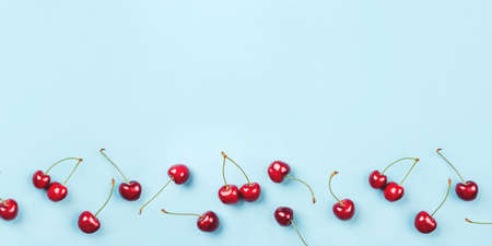Bright pattern of ripe cherries on a blue background. Flat lay, top view. Copy space for your text.の写真素材