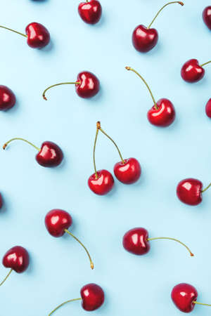 Bright pattern of ripe cherries on a blue background. Flat lay, top view.の写真素材