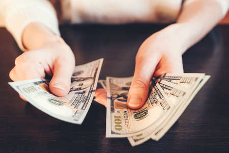 American cash dollars. A woman counts hundred dollar bills.の写真素材