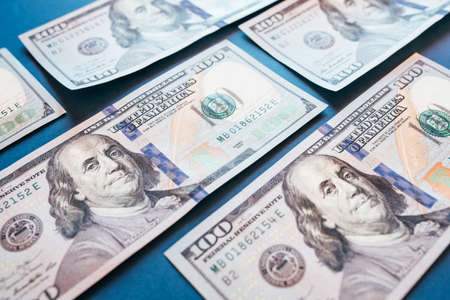 American cash dollars. Hundred-dollar bills in hand on blue background.の写真素材