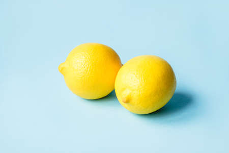 Two ripe lemons on a blue background. Minimal summer concept.の写真素材