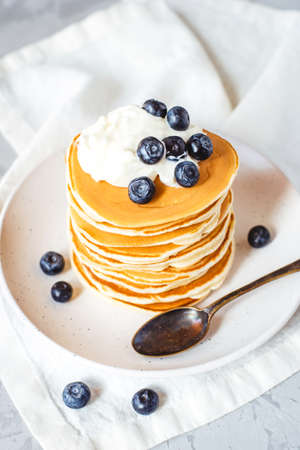 A stack of pancakes with fresh blueberries, buttercream and powdered sugar.の写真素材