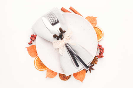 Thanksgiving autumn background. Plate with Cutlery and napkin decorated with autumn leaves, berries and spices. Top view.の写真素材