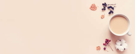 Autumn pastel background. A cup of hot coffee or tea with milk with autumn leaves and anise. Banner with copy space for text. Flat lay, top view.の写真素材