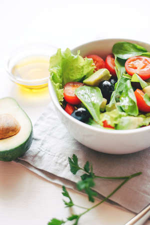 Fresh salad of avocado, cherry, arugula and olives made at home. Vegan food. The concept of healthy...