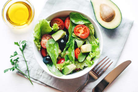 Fresh salad of avocado, cherry, arugula and olives made at home. Vegan food. The concept of healthy eating. Top view.の写真素材