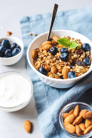 Baked granola with yogurt and blueberries on a gray table.の写真素材