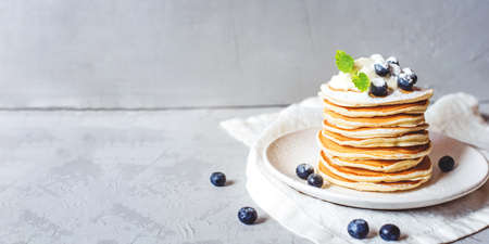 A stack of pancakes with fresh blueberries, buttercream and powdered sugar. Banner with copy space.の写真素材
