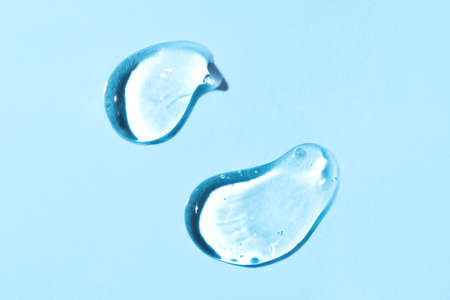 Transparent hyaluronic acid gel drops on a blue background.の写真素材