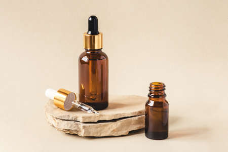 Two brown bottles of cosmetics on a natural beige background. Stone podium. Front view.の写真素材