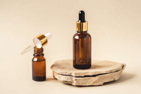 Two brown bottles of cosmetics on a natural beige background. Stone podium. Front view.の写真素材