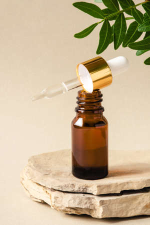 One brown bottle of cosmetics on a natural beige background. Stone podium. Front view.の写真素材