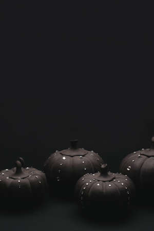 Ceramic pumpkins with rhinestones on a black background. Minimalistic background for autumn holidays with space for text.の写真素材