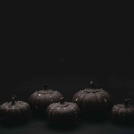 Ceramic pumpkins with rhinestones on a black background. Minimalistic background for autumn holidays with space for text.の写真素材