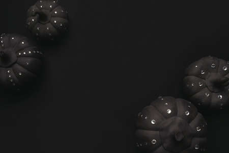 Ceramic pumpkins with rhinestones on a black background. Minimalistic background for autumn holidays with space for text. Flat lay, top view.の写真素材