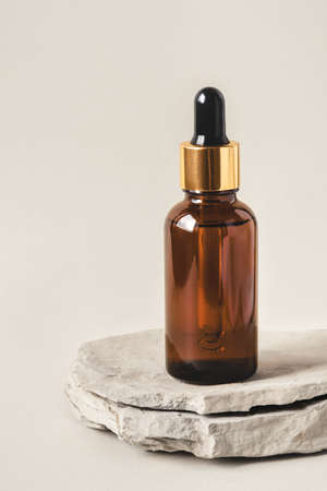 One brown bottle of cosmetics on a natural gray background. Stone podium. Front view.の写真素材