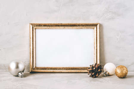 Golden photo frame and christmas decorations on gray background. Christmas, winter, new year concept. Copy space for text.の写真素材