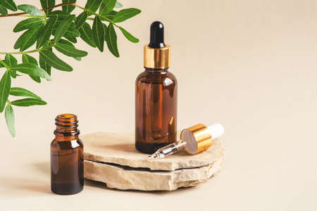 Two brown bottles of cosmetics on a natural beige background. Stone podium. Front view.の写真素材
