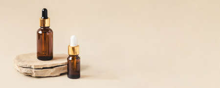 Two brown bottles of cosmetics on a natural beige background. Stone podium. Front view.の写真素材